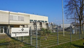 Tiefpumpwerk von außen mit einem Schild und dem Logo auf dem Zaun im Vordergrund